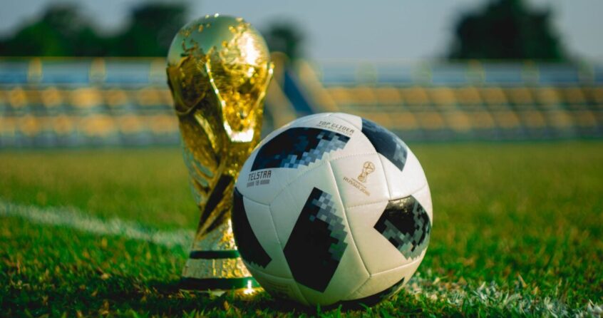 soccer ball beside trophy on soccer field
